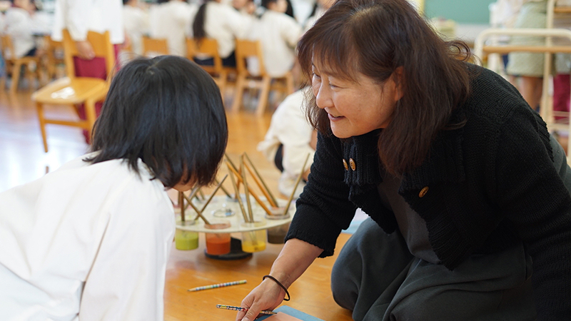 園児と顔を合わせる保育士の写真