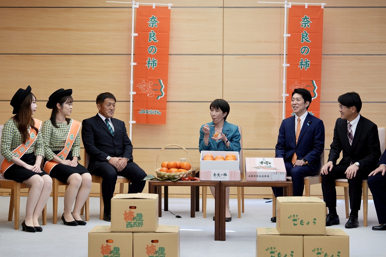 首相が奈良の柿をおいしそうに頬張る